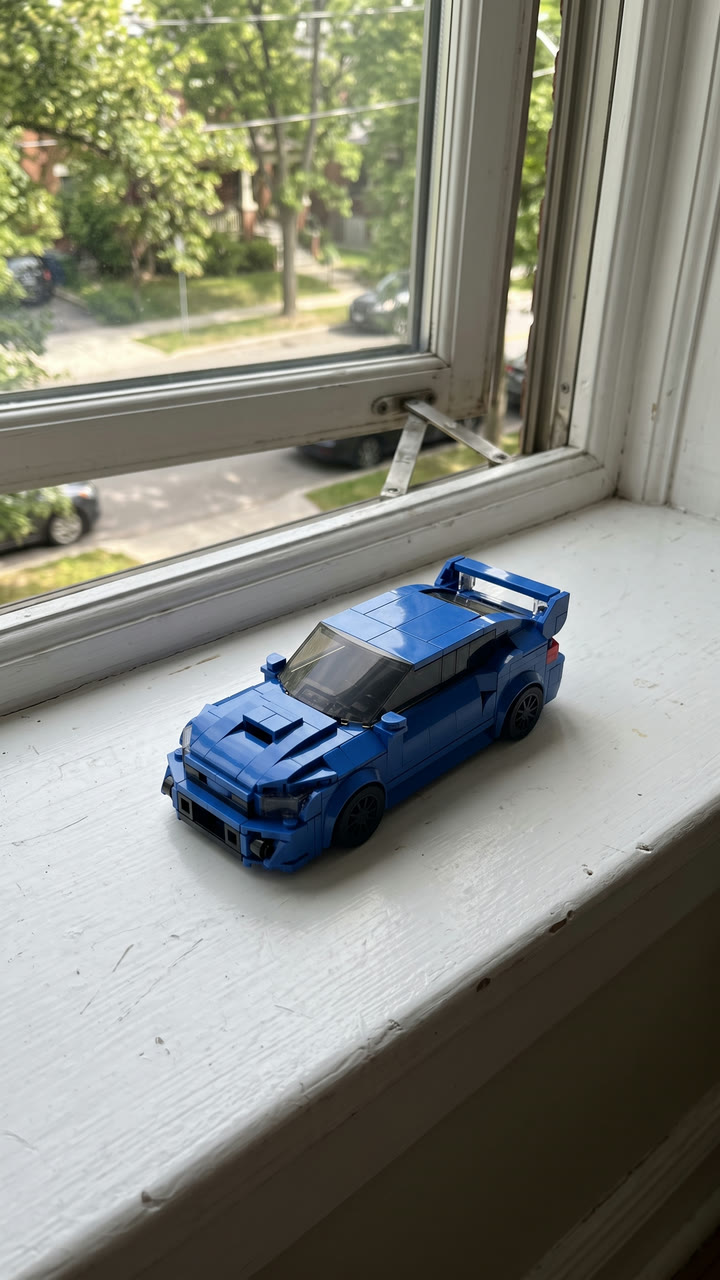 A blue brick-built rally car on a sunny windowsill