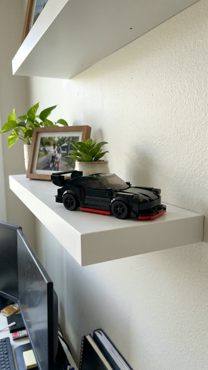A black brick-built coupe with red trim on a white floating shelf