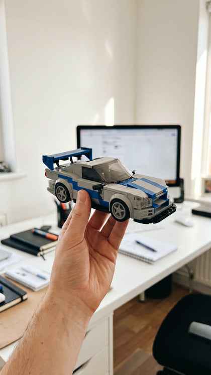 A silver and blue brick-built sports car held up in a bright office