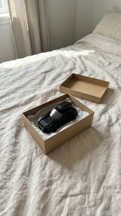 A black brick-built estate in an open gift box on a bed