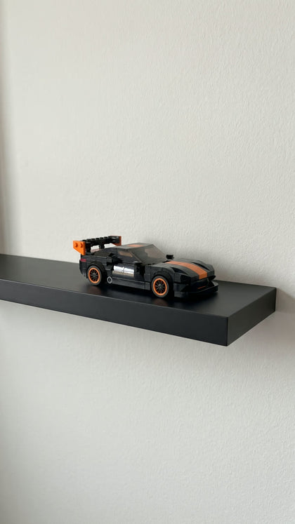 A black and orange brick-built sports car on a black floating shelf