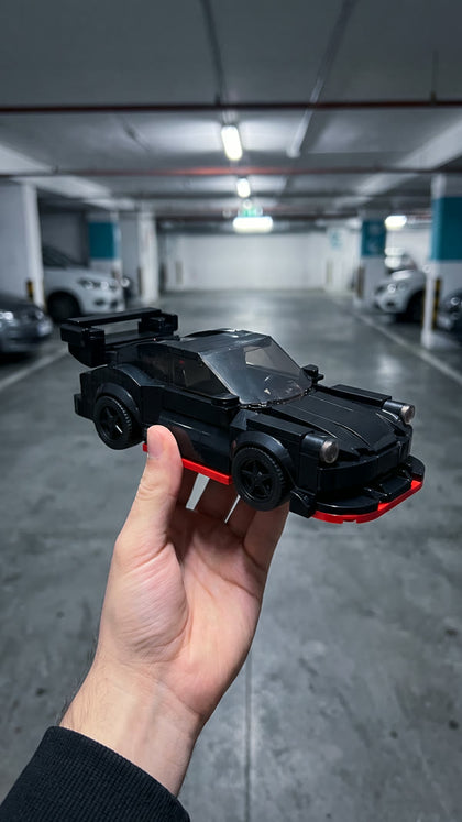 A black brick-built coupe with red trim held up in an underground car park
